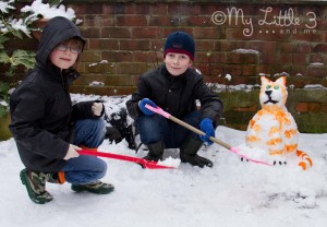 2 children with spades next to their snow cat.